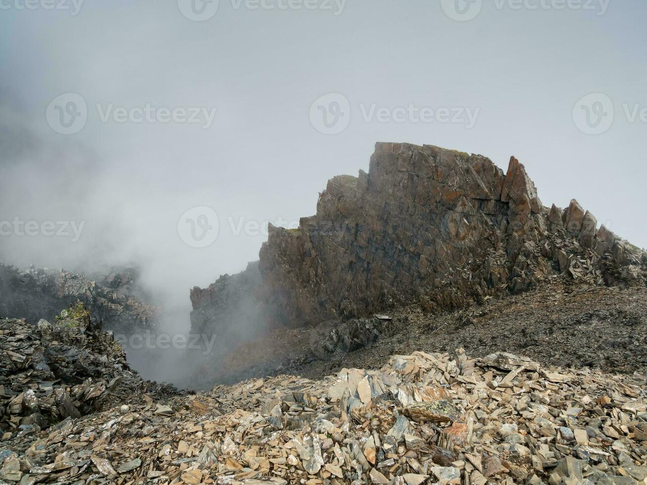 nebbioso montagna Visualizza a partire dal scogliera a molto alto altitudine. panoramico alpino paesaggio con bellissimo acuto rocce e canaloni nel Alba. bellissimo scenario su abisso bordo con acuto pietre. foto