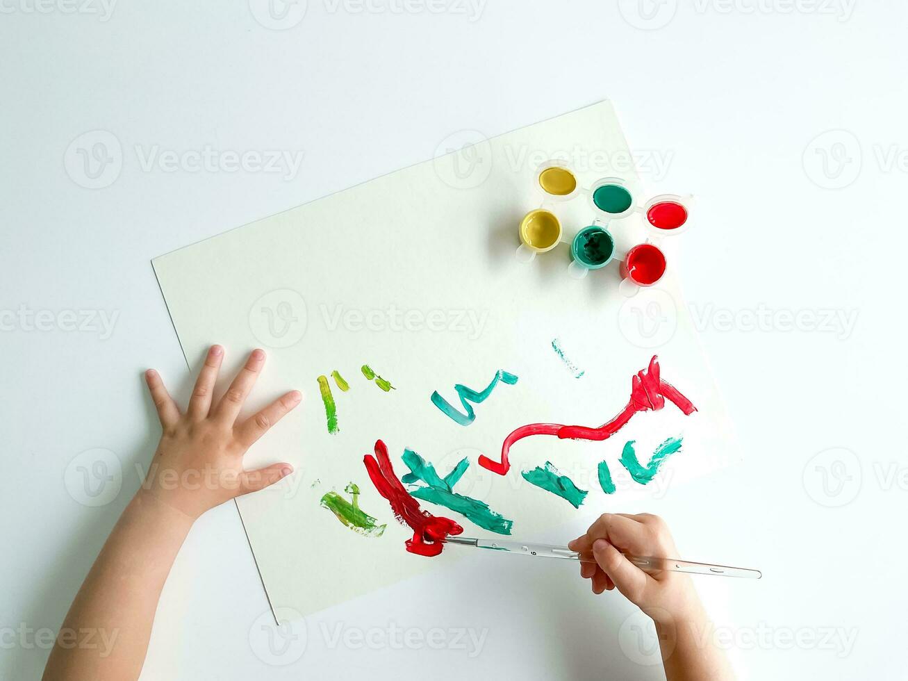 piccolo bambino disegna con vernici e spazzola su bianca tavolo. padri giorno foto