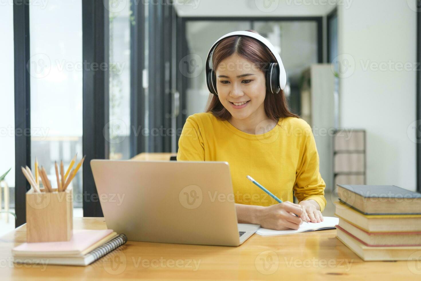 donna apprendimento in linea utilizzando il computer portatile e scrittura Appunti. foto