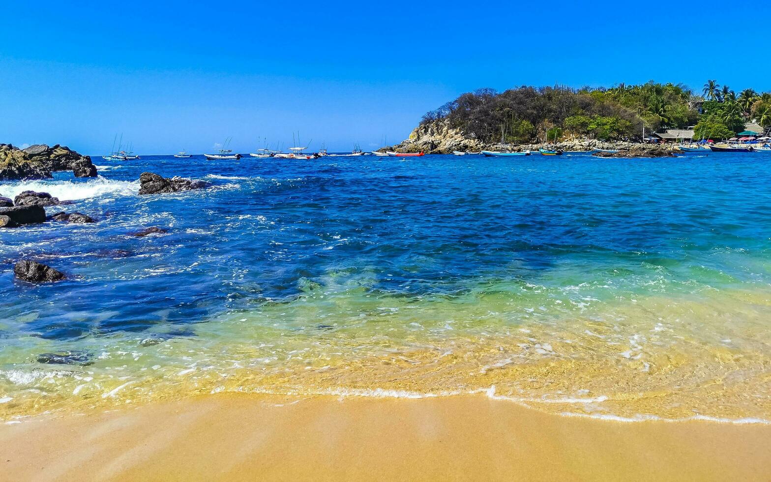 spiaggia sabbia blu turchese acqua onde rocce panorama puerto escondido. foto