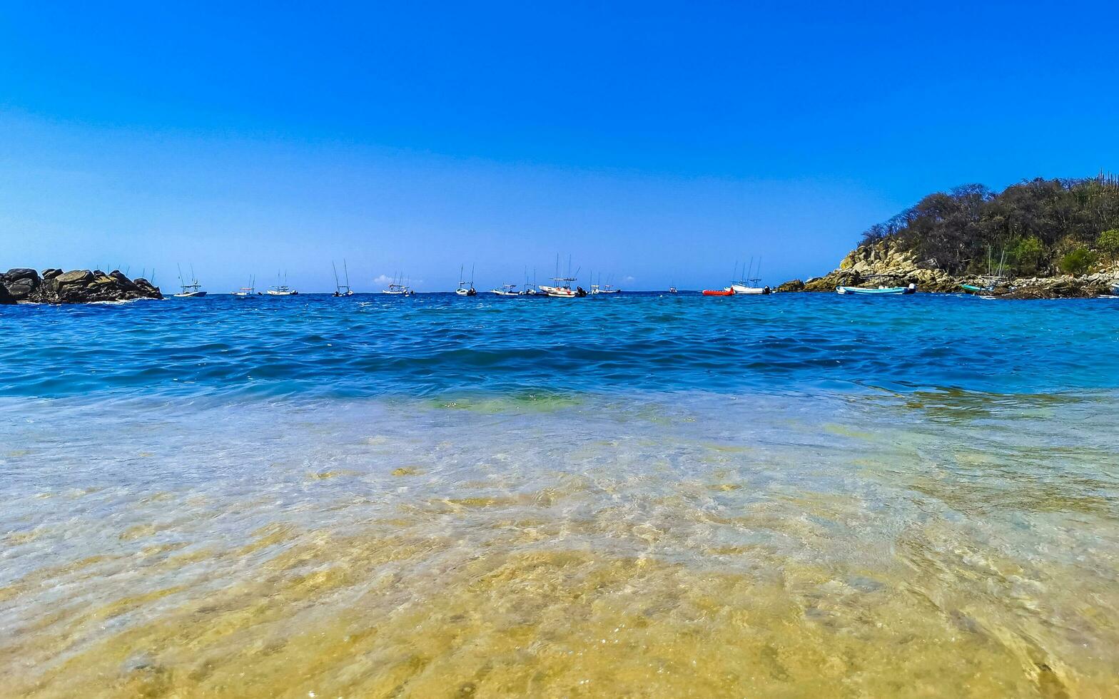 spiaggia sabbia blu turchese acqua onde rocce panorama puerto escondido. foto