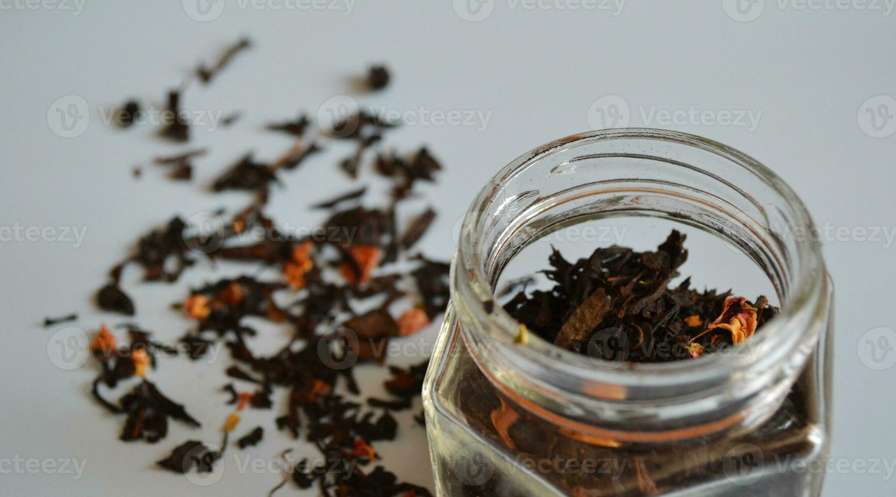 foglia tè con pezzi di frutta nel un' barattolo, sparpagliato Tè, nero Tè, un' vaso di tè su un' grigio sfondo, internazionale tè giorno foto