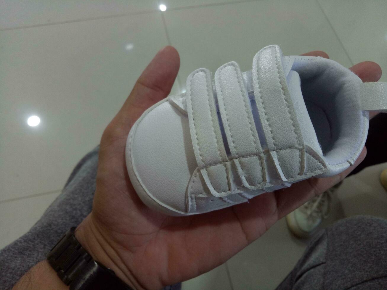 foto di un' carino poco bianca bambino scarpa con triplicare adesivo