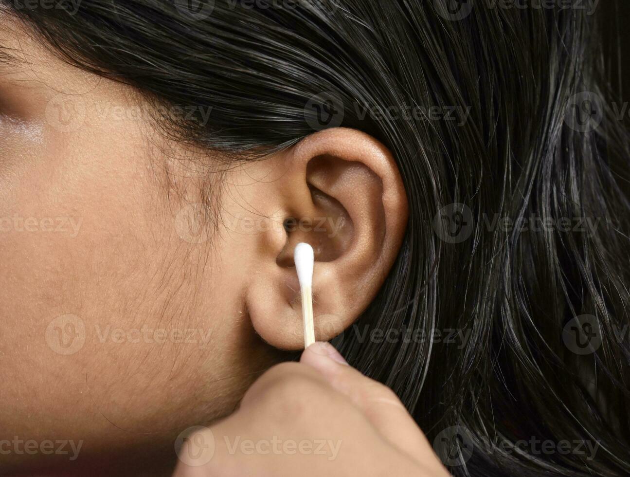 donna pulisce orecchio delicatamente con auricolare, cura e pulizia foto