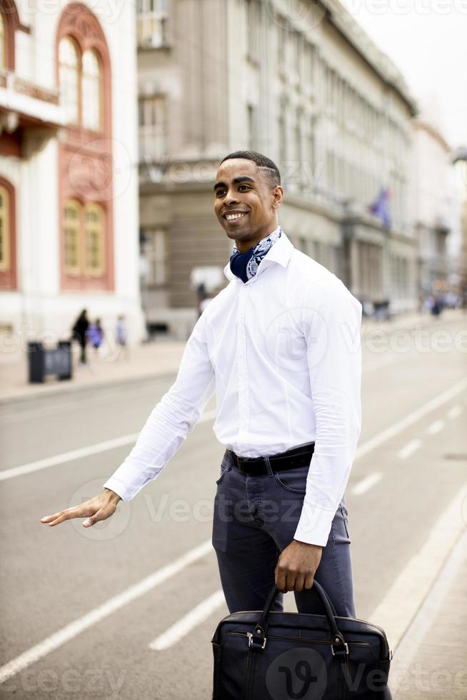 giovane uomo d'affari afroamericano waitng un taxi su una strada foto