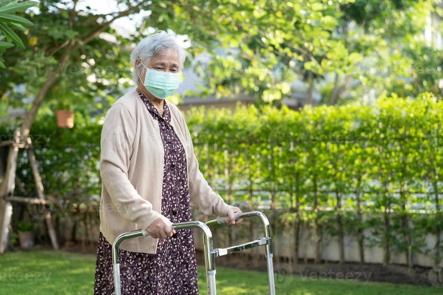 La donna anziana anziana o anziana asiatica cammina con il deambulatore e indossa una maschera per proteggere l'infezione di sicurezza covid 19 coronavirus foto