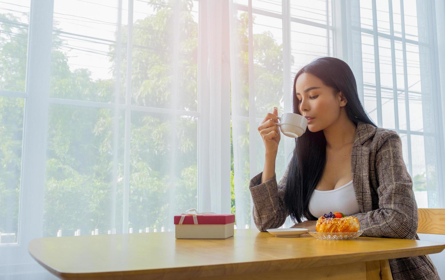 bella donna seduta a mangiare pane e caffè del mattino in vacanza e la luce risplende dall'esterno foto