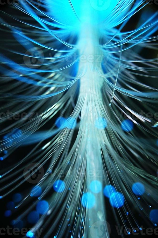 una sorprendente e vibrante macro di tubi ottici in fibra blu che si illuminano creando scintillii e luccichii con sfondo nero foto