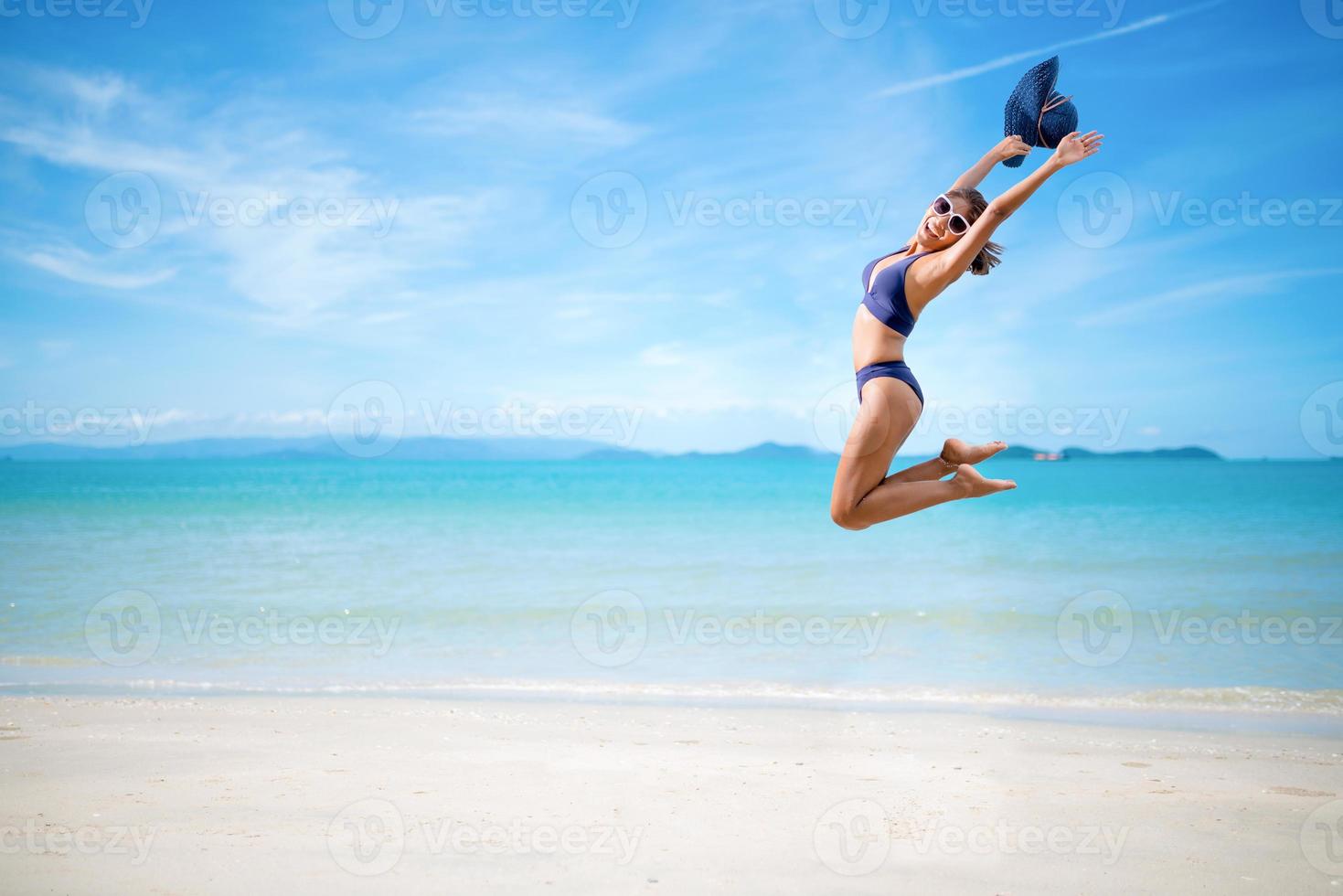 donna sexy in bikini blu che salta sulla spiaggia foto