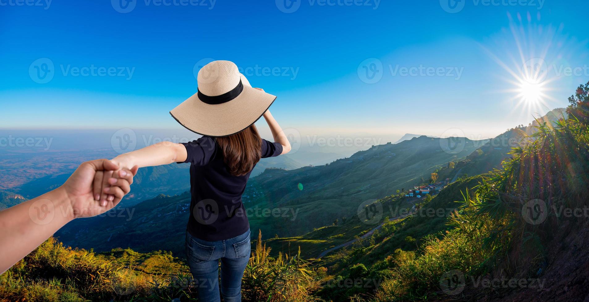 donna che tiene la mano di suo marito mentre corrono insieme sulla montagna foto