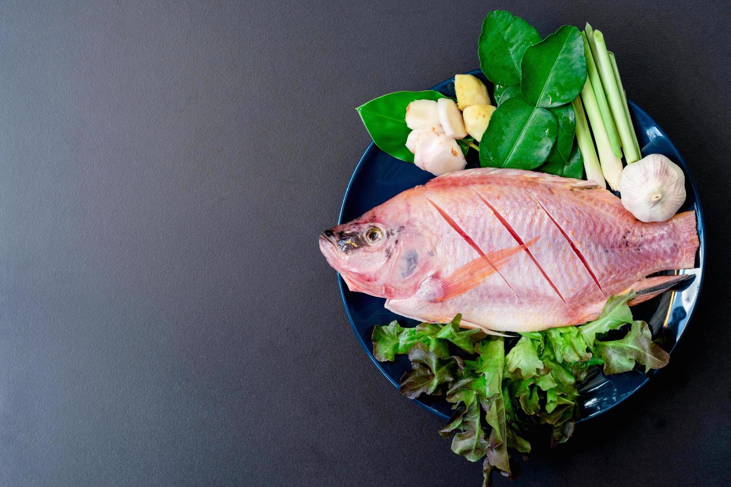 vista dall'alto di pesce fresco e verdure in piatti in ceramica preparati per la cottura con lo spazio della copia foto