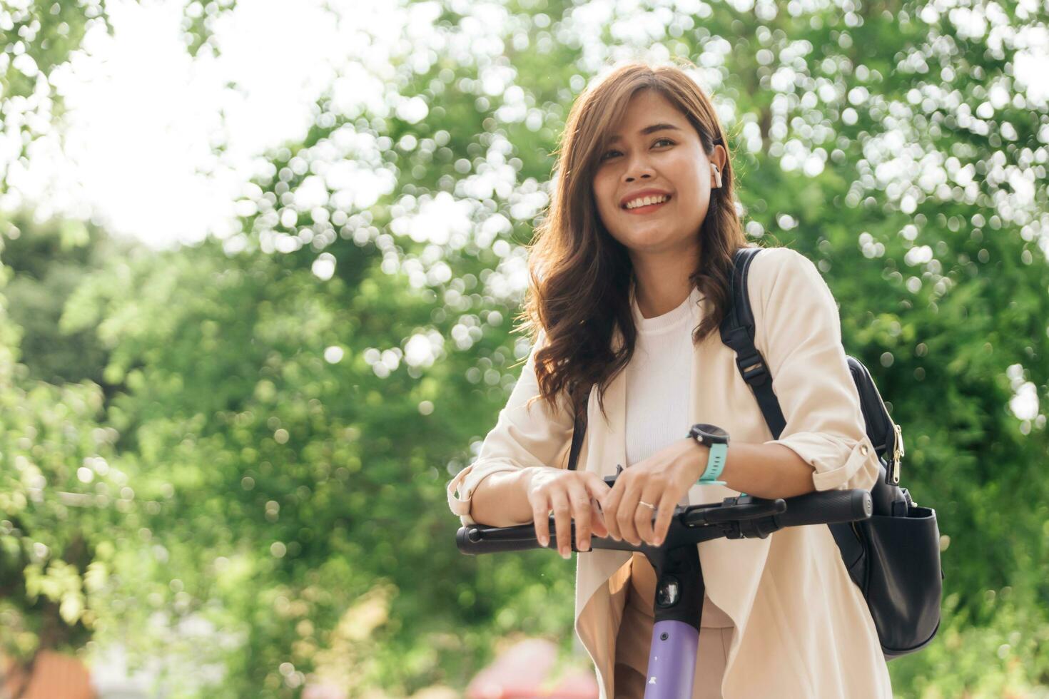 giovane asiatico donna equitazione elettrico scooter nel il parco con verde sfondo. foto