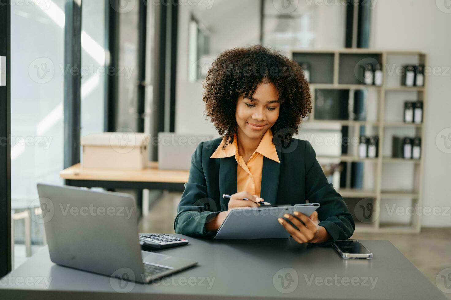 fiducioso attività commerciale esperto attraente sorridente giovane donna digitando il computer portatile ang Tenere digitale tavoletta su scrivania nel ufficio. foto