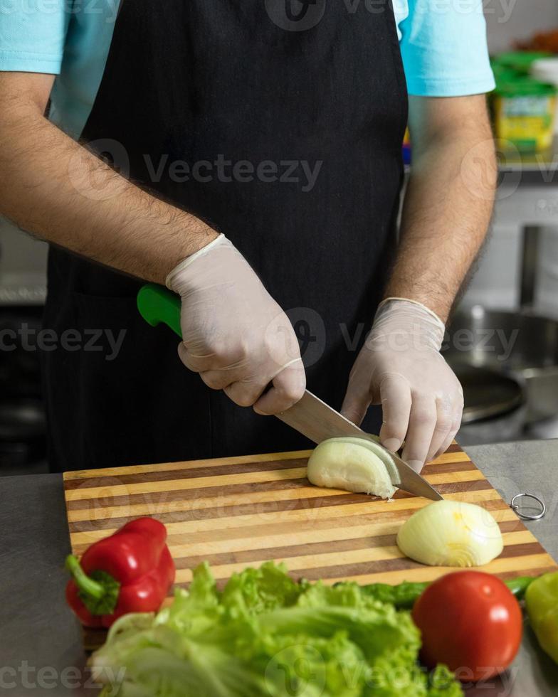 chef del ristorante che prepara un'insalata, tagliando la cipolla foto