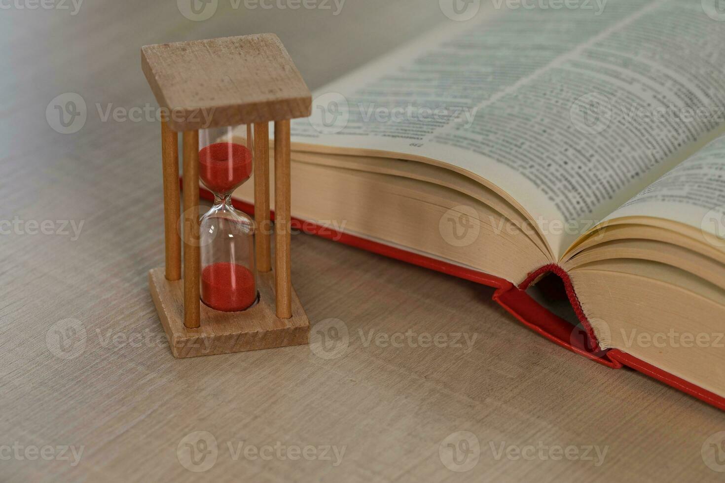 sabbia orologio su un' tavolo. dizionario nel il sfondo. foto