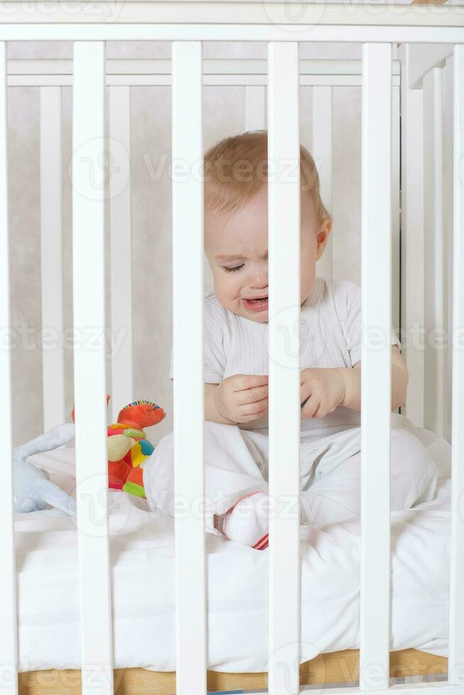 un' bambino ragazza di otto mesi sta piangendo nel sua letto foto