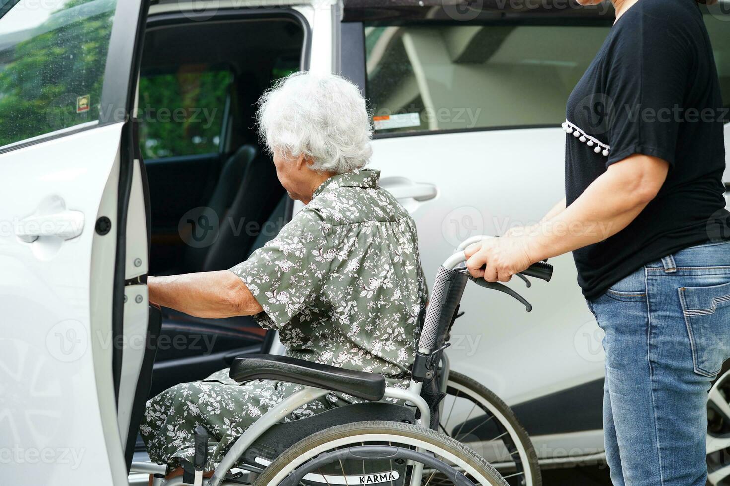 il caregiver aiuta il paziente con disabilità della donna anziana asiatica a salire nella sua macchina, concetto medico. foto