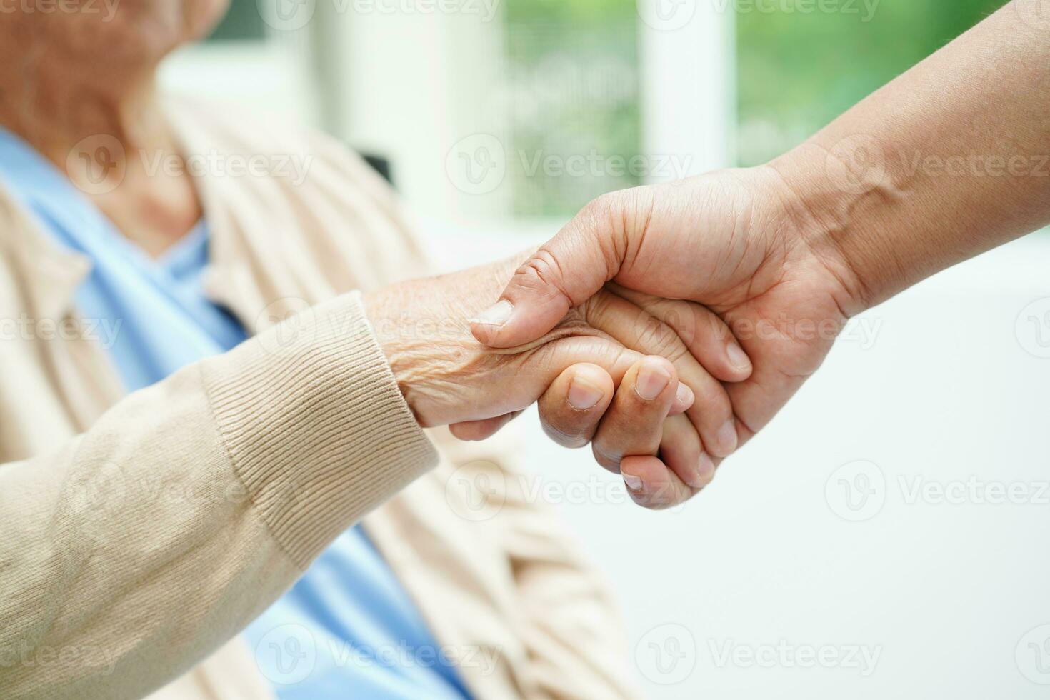 badante che si tiene per mano paziente donna anziana asiatica, aiuto e cura in ospedale. foto
