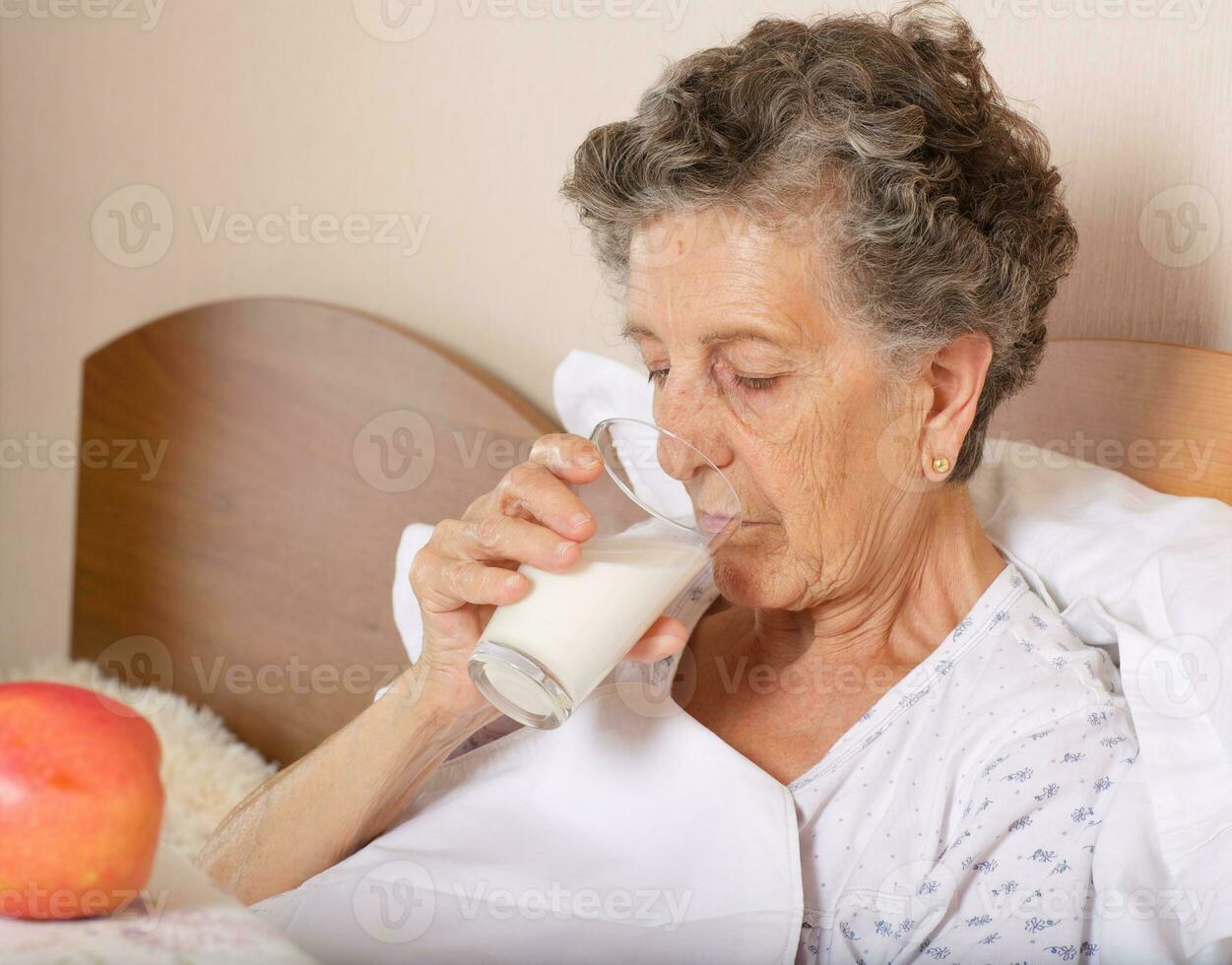 vecchio donna bevande alcuni latte nel il mattina foto