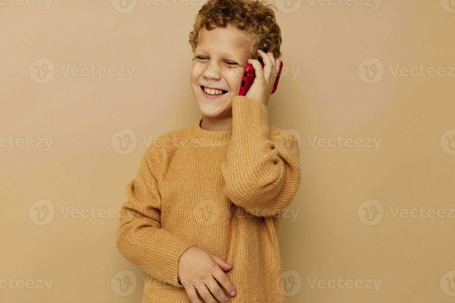 allegro ragazzo parlando su il Telefono su un' beige sfondo foto