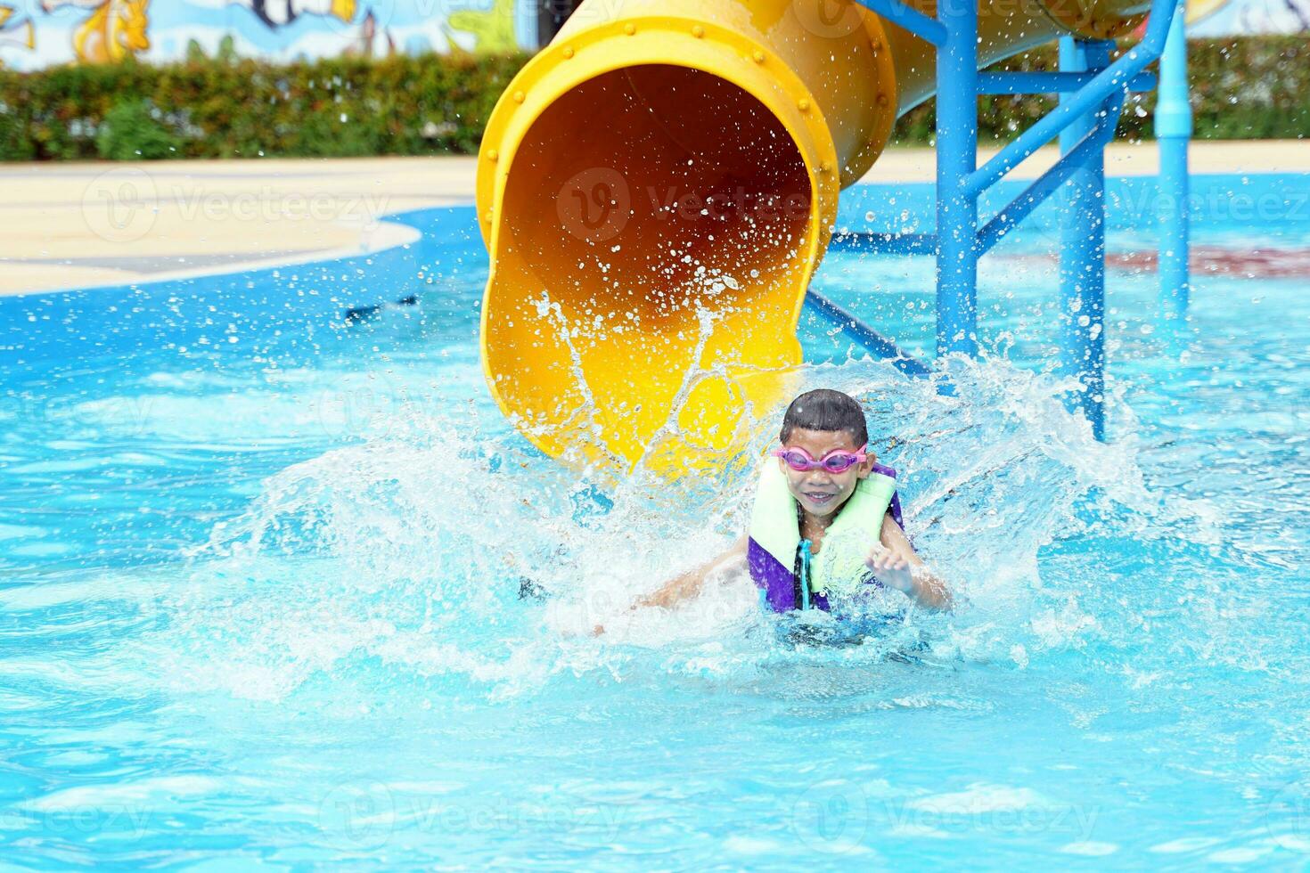 bambini giocare acqua scivoli nel il acqua parco. lui era contento e avendo divertimento, particolarmente quando lui scivolato in il piscina e il acqua schizzato. morbido e selettivo messa a fuoco. foto