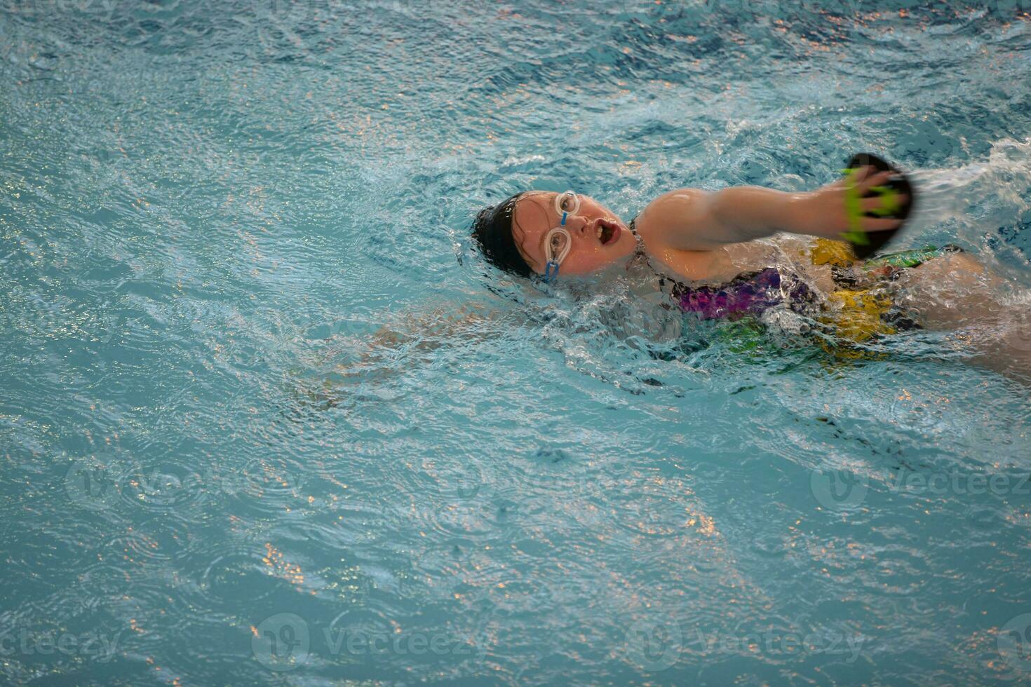 ragazza nel un' nuoto berretto e nuoto occhiali nel il piscina. il bambino è impegnato nel il nuoto sezione. foto