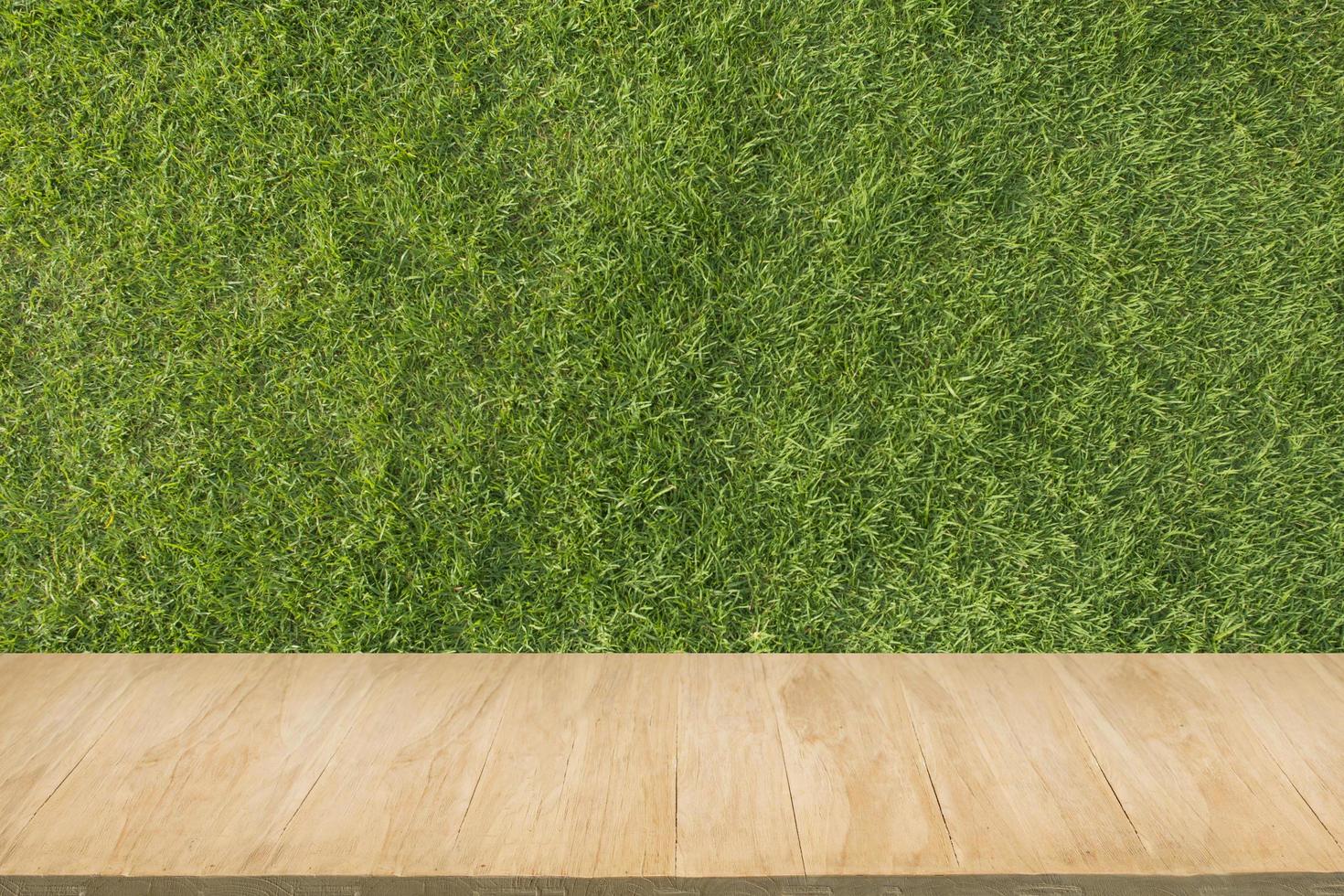 pavimento in legno con sfondo di erba verde foto