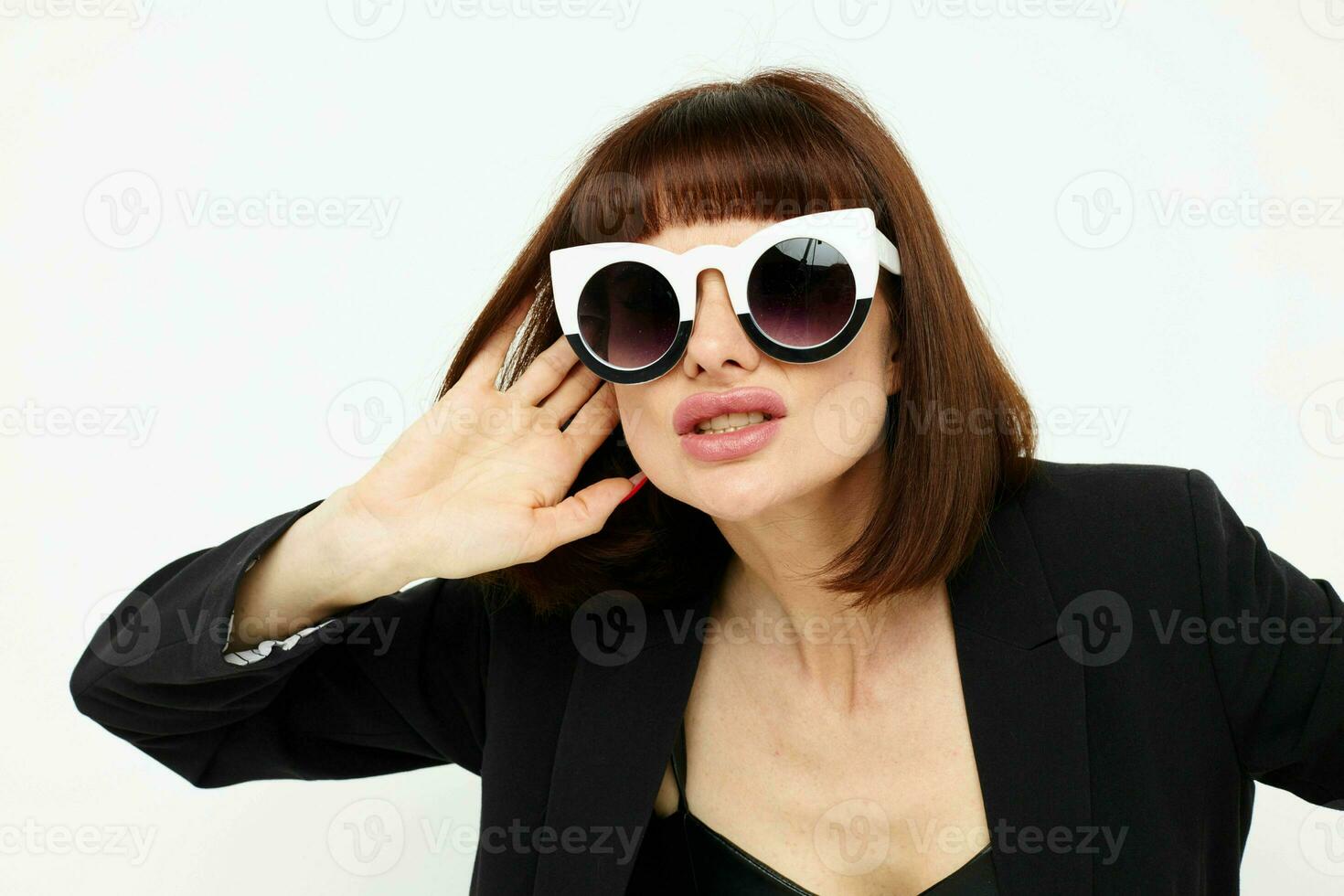 ritratto di un' donna in posa con occhiali da sole un' pelle completo da uomo nero giacca isolato sfondo foto