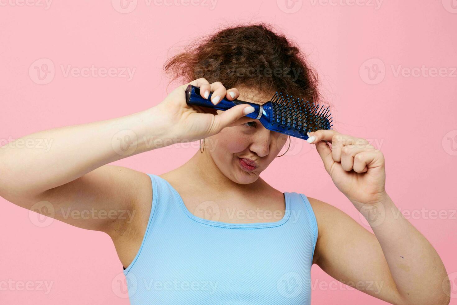 attraente donna schizzinoso facciale espressione pettine capelli rosa colore sfondo inalterato foto