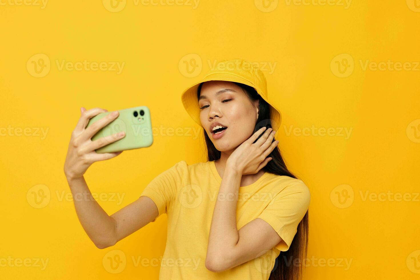 ritratto asiatico bellissimo giovane donna nel un' giallo cappello e maglietta parlando su il Telefono stile di vita inalterato foto