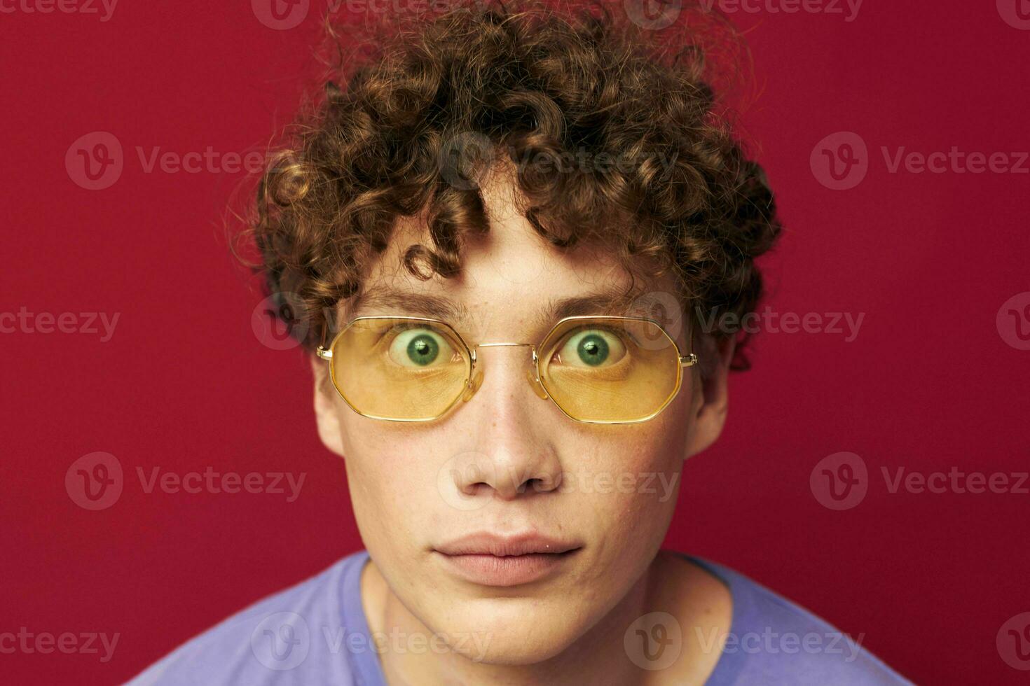 ritratto di un' giovane Riccio uomo nel giallo bicchieri viola maglietta emozioni stile di vita foto