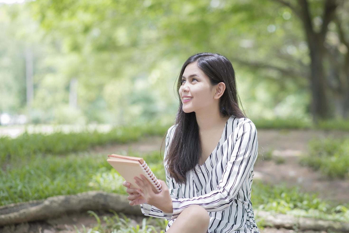 donna attraente che legge un libro nel parco foto
