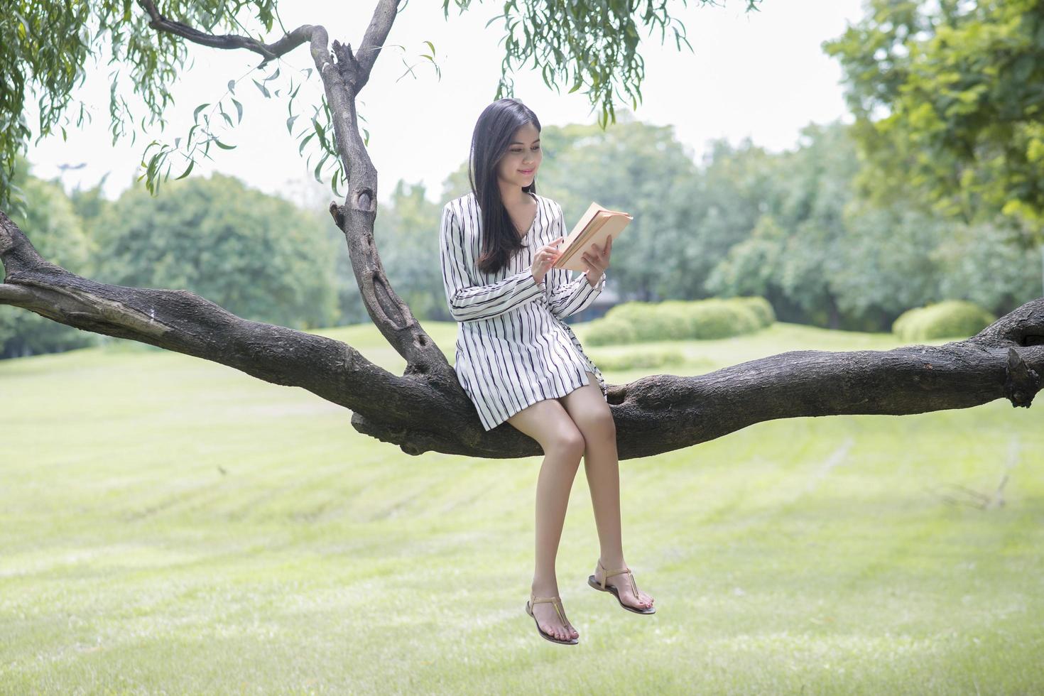donna attraente che legge un libro nel parco foto