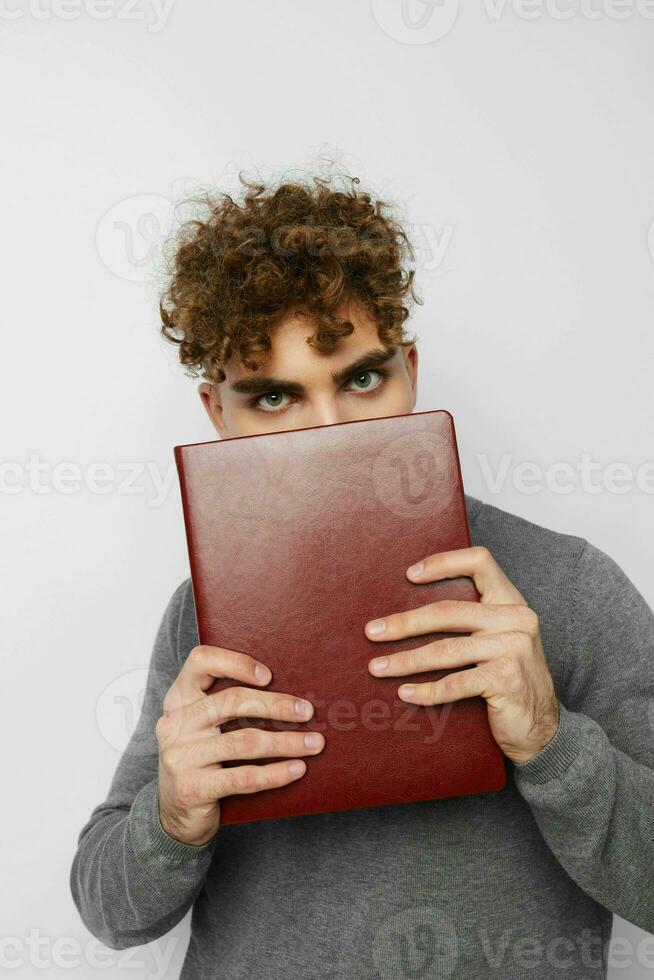 carino tipo con Riccio capelli con un' libro nel il suo mani formazione foto