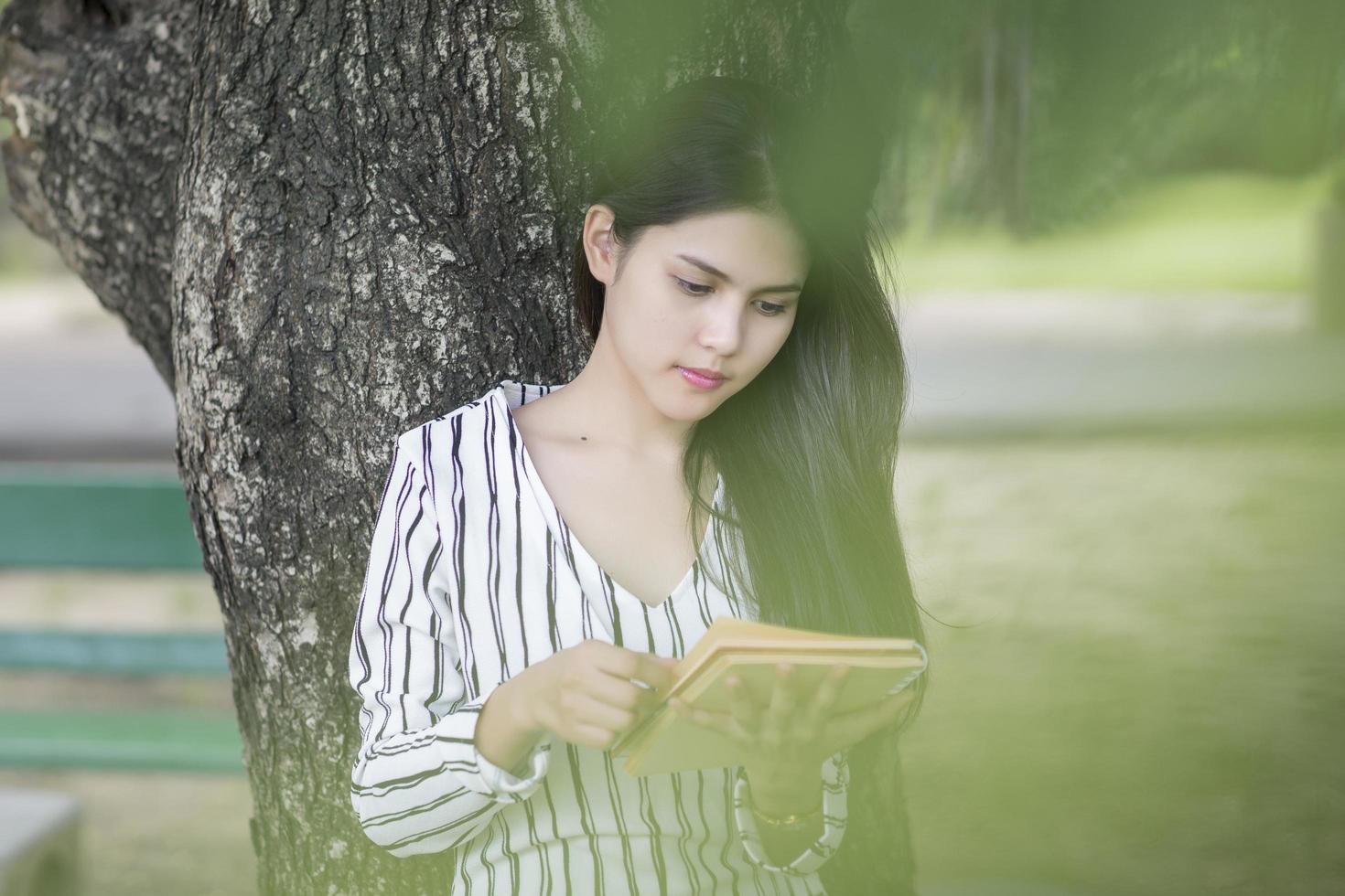 donna attraente che legge un libro nel parco foto