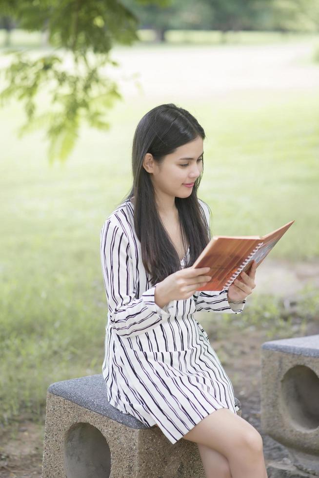 donna attraente che legge un libro nel parco foto