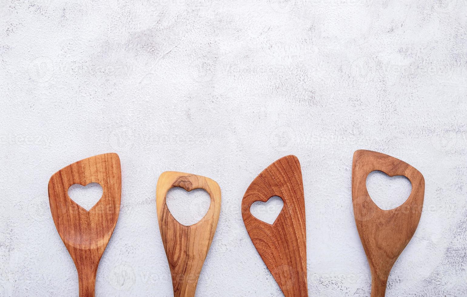 varie forme di cuore di utensili da cucina in legno cucchiai di legno e spatola di legno su sfondo di cemento con spazio piatto e copia foto