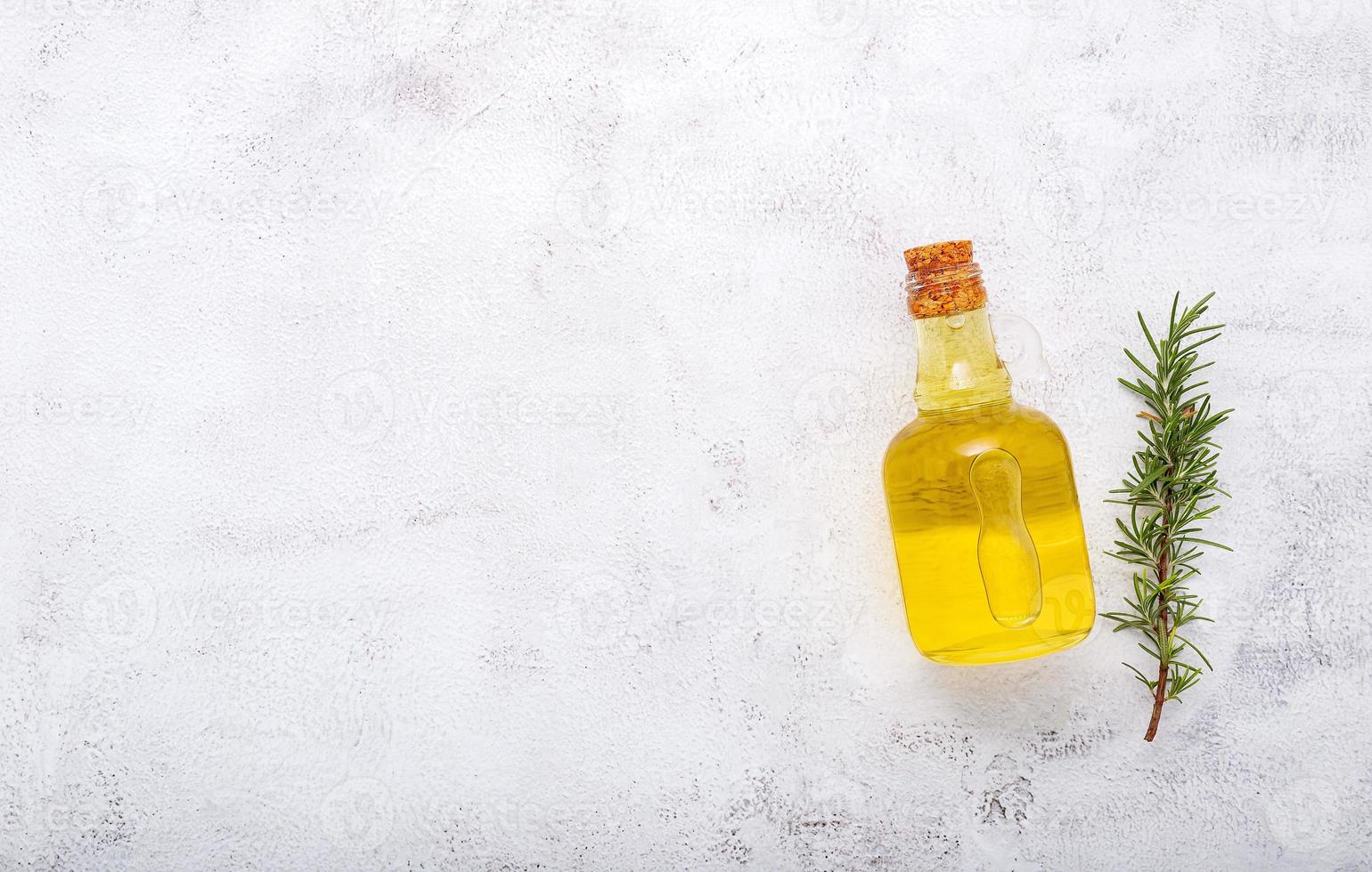 bottiglia di vetro di olio d'oliva e ramo di rosmarino istituito su sfondo bianco di cemento foto