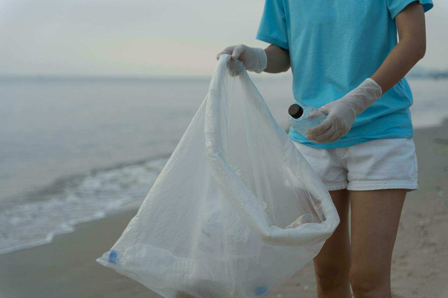Salva oceano. volontario raccogliere su spazzatura spazzatura a il spiaggia e plastica bottiglie siamo difficile decomporsi impedire danno acquatico vita. terra, ambiente, greening pianeta, ridurre globale riscaldamento, Salva mondo foto