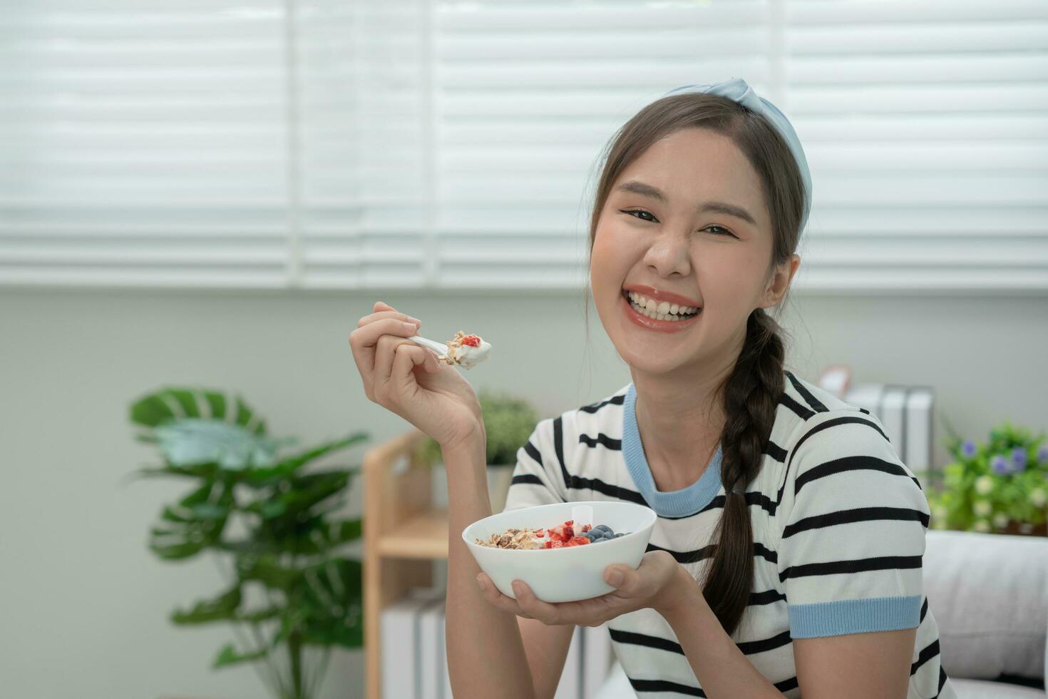 salutare cibo. bellissimo femmina ragazza godere mangiare Yogurt, muesli, fresco frutta su prima colazione Salute nel Casa. contento giovane donna Sorridi su mattina bene emozione. dieta, disintossicazione, dieta, pulito mangiare, vegetariano foto