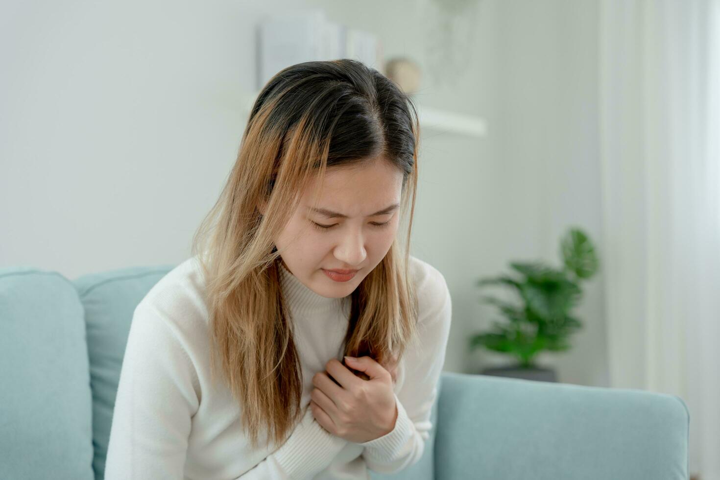 mano hold il petto con cuore attacco sintomi, asiatico donna avere il petto dolore causato di cuore patologia, perdere, dilatazione, allargata coronario cuore, stampa su il il petto con un' doloroso espressione foto