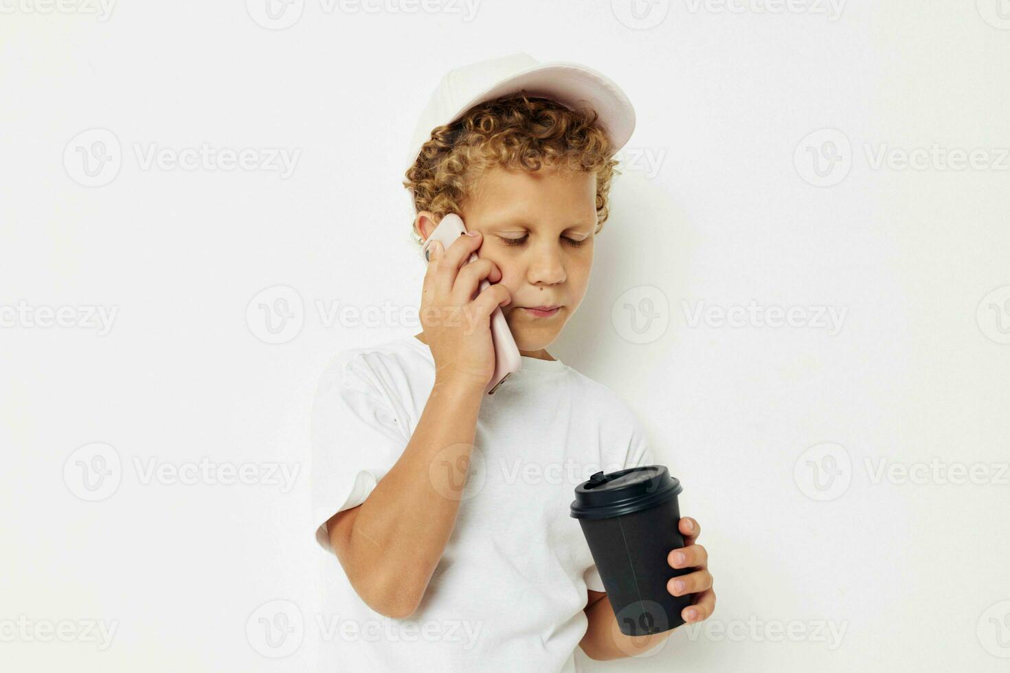 carino ragazzo nel un' bianca maglietta berretto con un' Telefono nel un' bicchiere con un' bevanda stile di vita inalterato foto