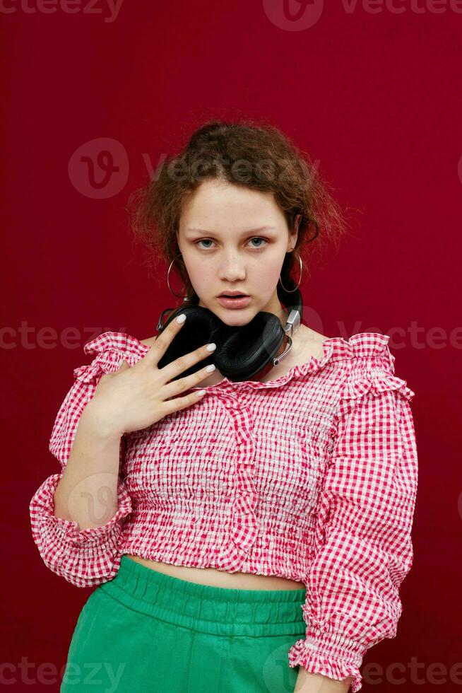 allegro ragazza con cuffie nel un' rosa camicetta musica tecnologia rosso sfondo foto