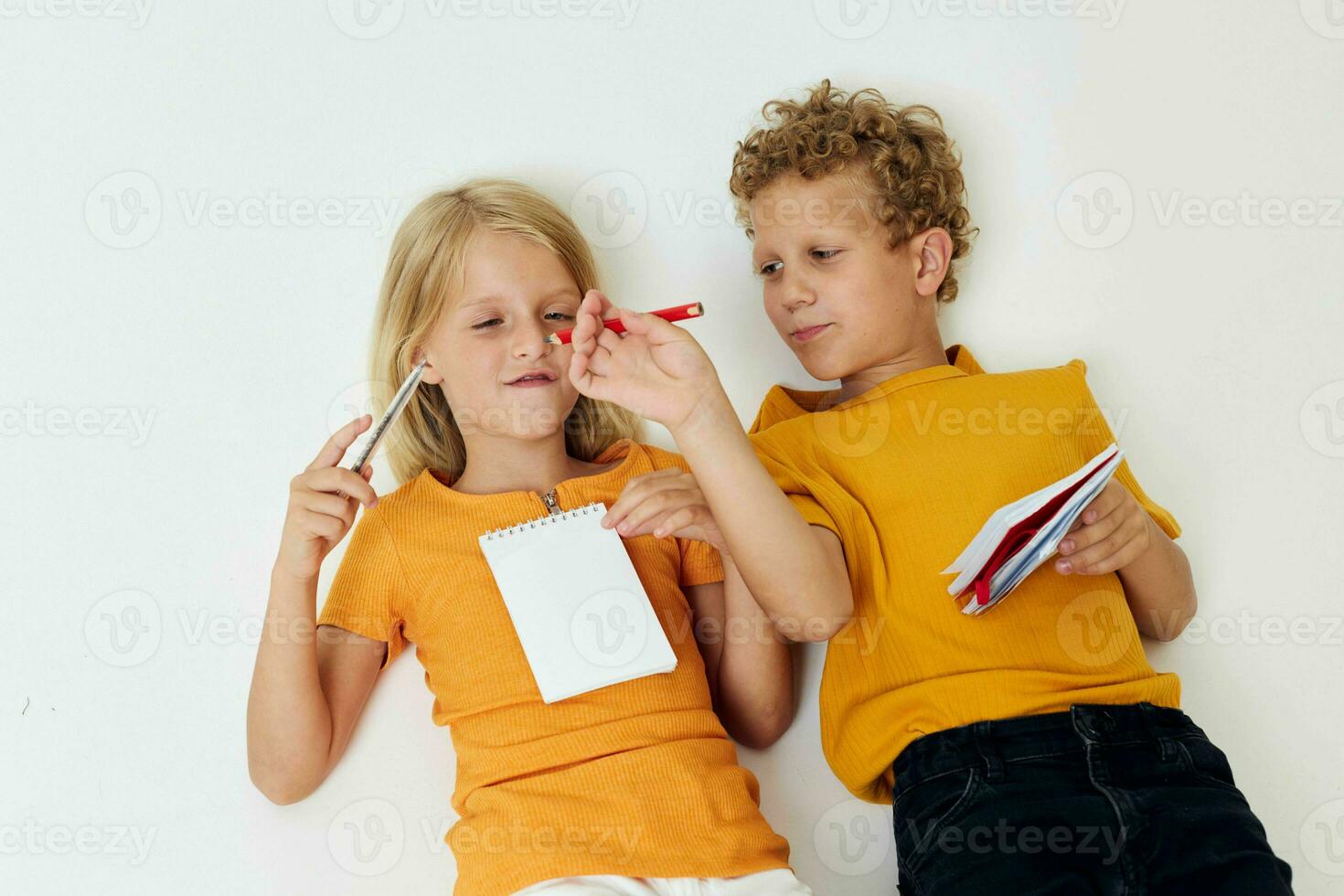 piccolo bambini menzogna su il pavimento con taccuini e matite isolato sfondo inalterato foto