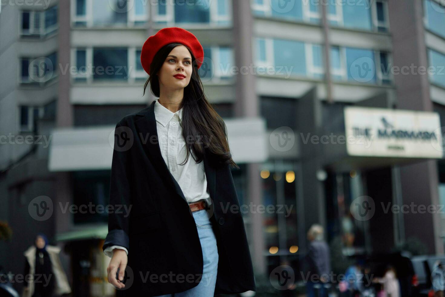 un' attività commerciale donna passeggiate nel il città contro il fondale di ufficio edifici, elegante alla moda Abiti e trucco, primavera camminare, viaggio. foto