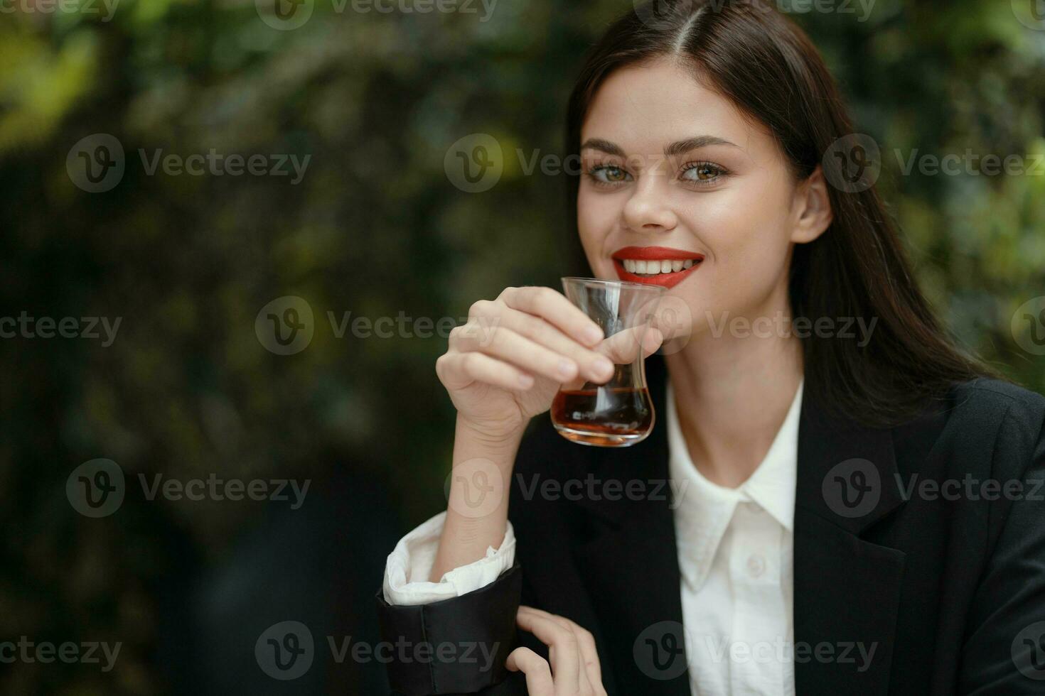 donna Sorridi con denti potabile tè nel un' bar a partire dal un' Turco bicchiere boccale su il strada foto