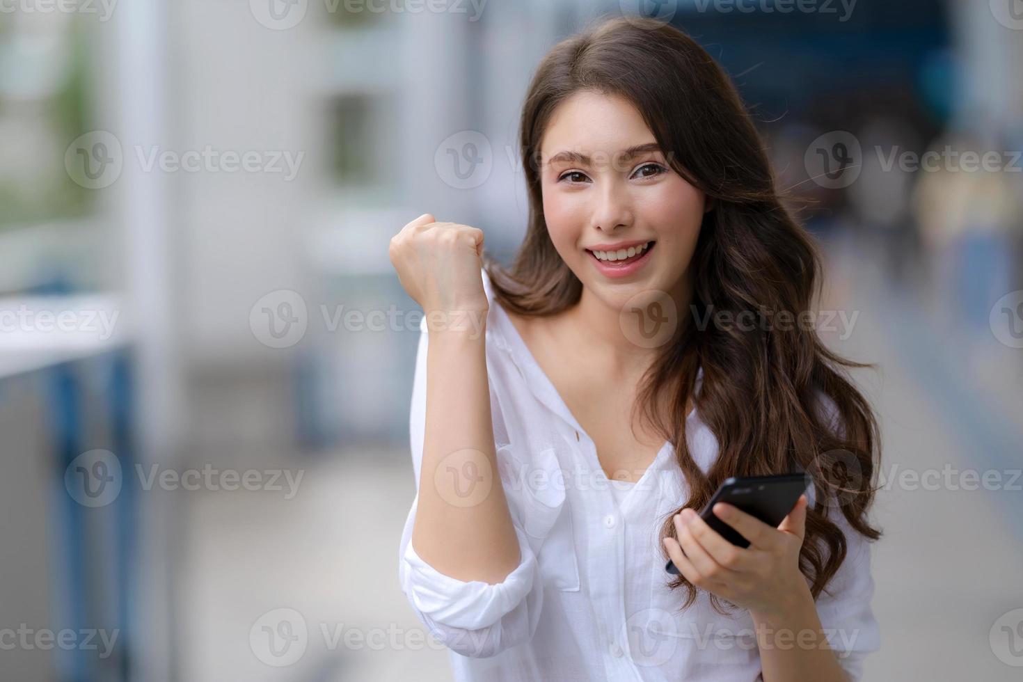 ritratto di giovane donna con faccina sorridente utilizzando un telefono cammina in una città foto