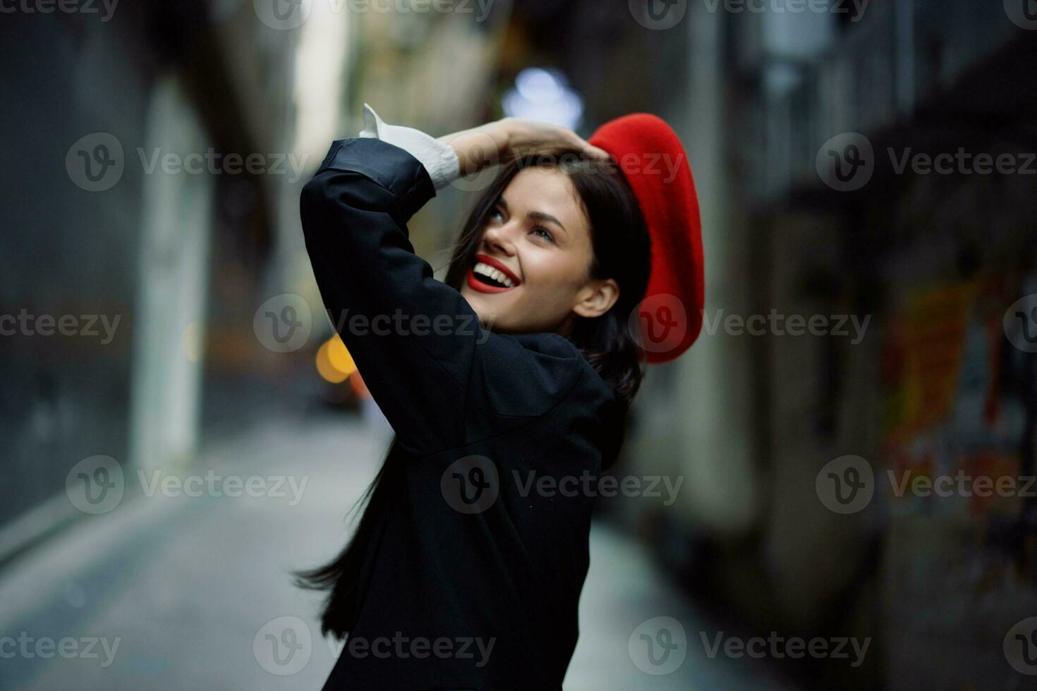 moda donna Sorridi con denti e divertimento turista nel elegante Abiti nel giacca e rosso berretto a piedi giù stretto città strada volante capelli, viaggiare, francese stile, cinematico colore, retrò Vintage ▾ stile. foto