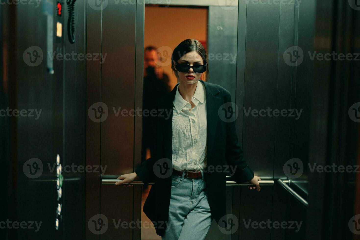 elegante donna nel nero giacca e occhiali da sole in posa nel ascensore, moda modello, buio cinematico leggero e colore, fascino Vintage ▾ foto