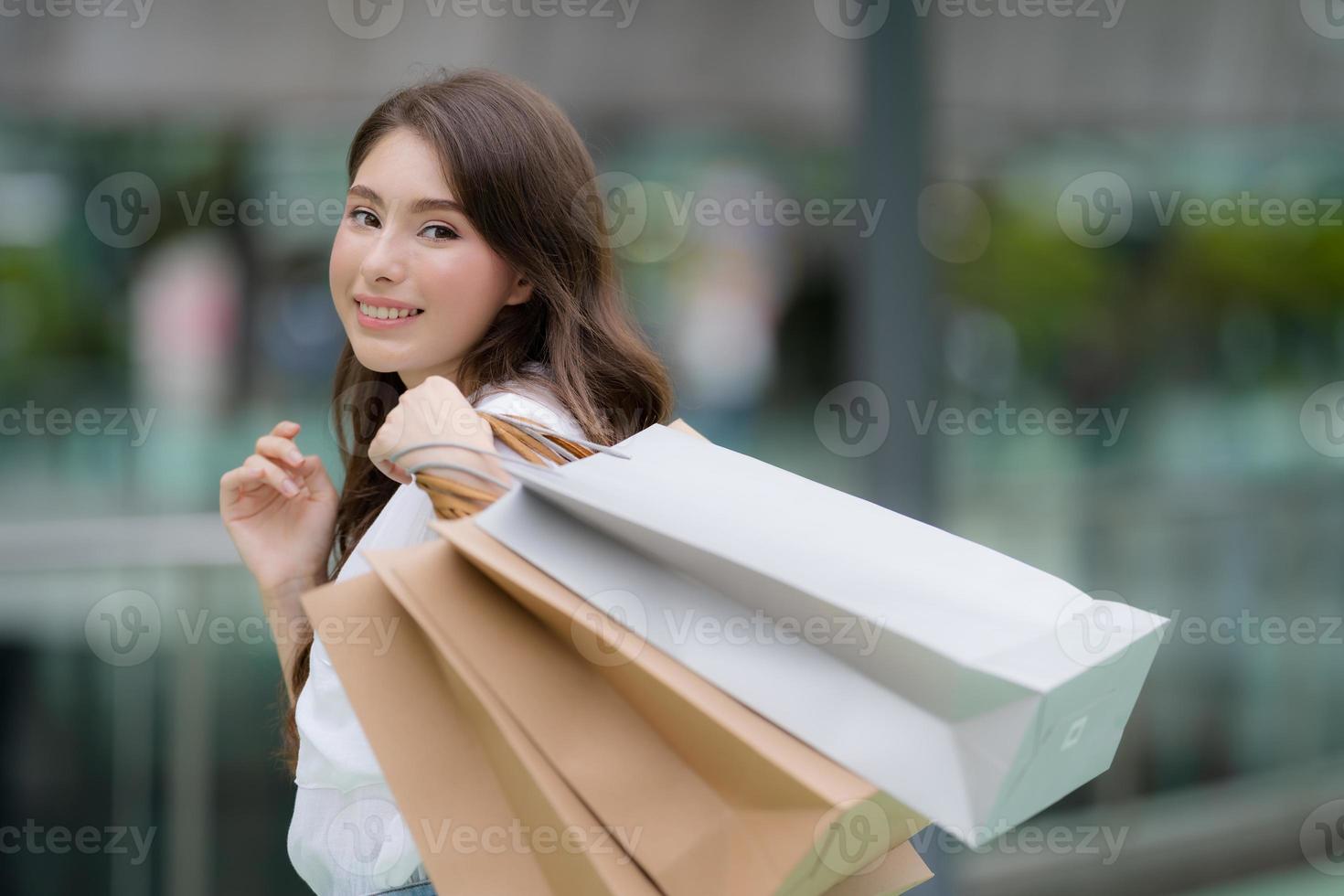 ritratto all'aperto di donna felice tenendo le borse della spesa e volto sorridente foto